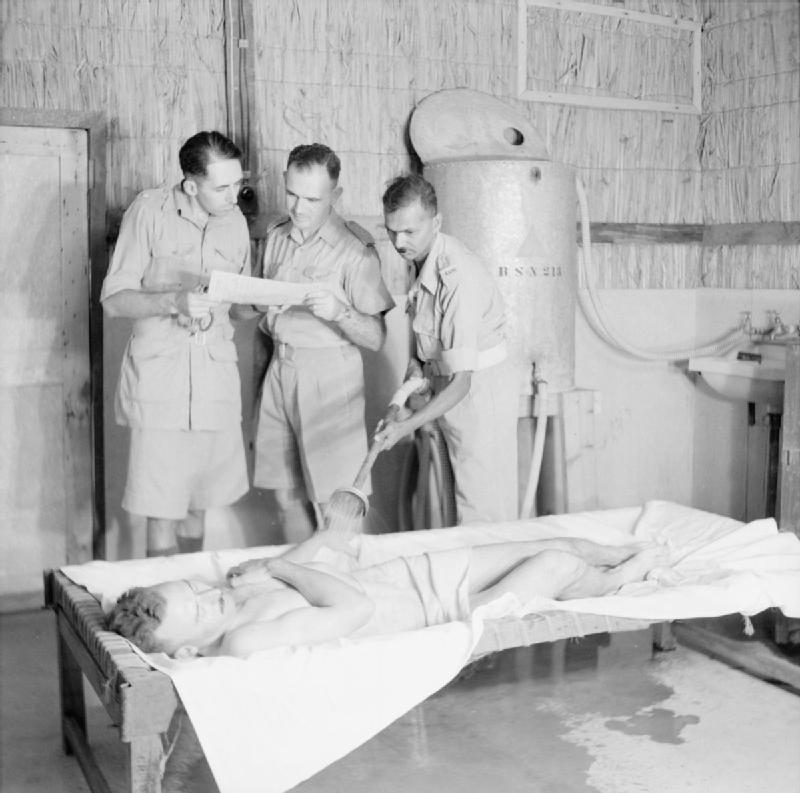 Clinical treatment photograph showing a heat casualty undergoing active external cooling; rapid whole-body cooling, preferably cold-water immersion for severe or exertional heat stroke, is central to management.