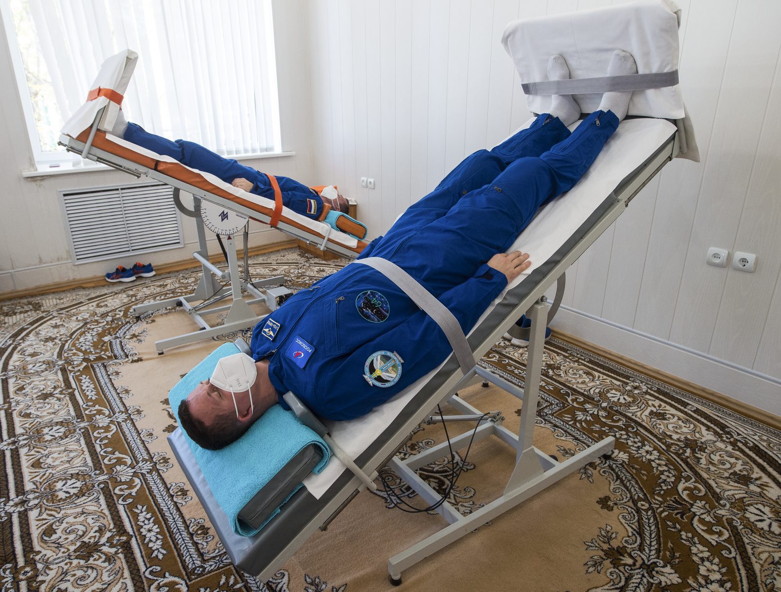 A participant secured on a head-up tilt table while blood pressure and heart rate are monitored, with a legend explaining that specialist provocation testing is used when bedside assessment is inconclusive or autonomic disease is suspected.